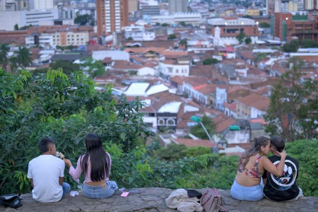 People enjoy the view of the city from a hill in the San Antonio neighbourhood in Cali, Colombia on February 16, 2026. The San Antonio neighborhood, known as the heart of "Old Cali", is a historic and bohemian area of colonial architecture, famous for its colorful facades and its location on a hill with panoramic views of the city. (Photo by Joaquín SARMIENTO / AFP)