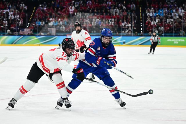 Canada's #17 Ella Shelton (L) fights for the puck with USA's #22 Tessa Janecke  during the women's gold medal ice hockey match between USA and Canada at the Milano Santagiulia Ice Hockey Arena during the Milano Cortina 2026 Winter Olympic Games in Milan, on February 19, 2026. (Photo by JULIEN DE ROSA / AFP)