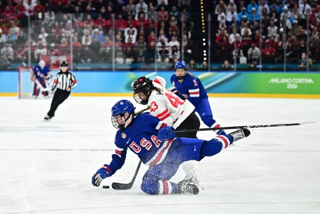 Canada's #43 Kristin O'Neill (R) fights for the puck with USA's #13 Grace Zumwinkle  during the women's gold medal ice hockey match between USA and Canada at the Milano Santagiulia Ice Hockey Arena during the Milano Cortina 2026 Winter Olympic Games in Milan, on February 19, 2026. (Photo by JULIEN DE ROSA / AFP)