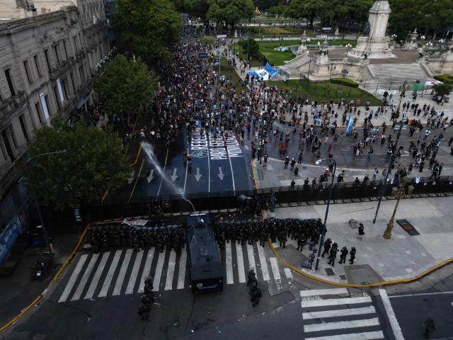 An aerial view shows a police water cannon spraying water at demonstrators outside the Congress building, where Argentina's President Javier Milei's labour reform is being treated, in Buenos Aires on February 19, 2026. Shops and supermarkets closed, public transport was scarce and garbage went uncollected on February 19, 2026 as Argentine workers staged the fourth general strike of President Javier Milei's term, this time to protest labor reforms. (Photo by TOMAS CUESTA / AFP)