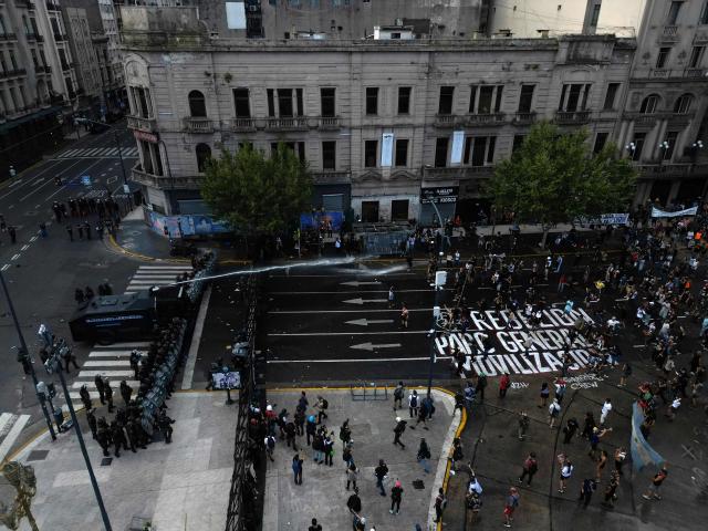 An aerial view shows a police water cannon spraying water at demonstrators outside the Congress building, where Argentina's President Javier Milei's labour reform is being treated, in Buenos Aires on February 19, 2026. Shops and supermarkets closed, public transport was scarce and garbage went uncollected on February 19, 2026 as Argentine workers staged the fourth general strike of President Javier Milei's term, this time to protest labor reforms. (Photo by TOMAS CUESTA / AFP)
