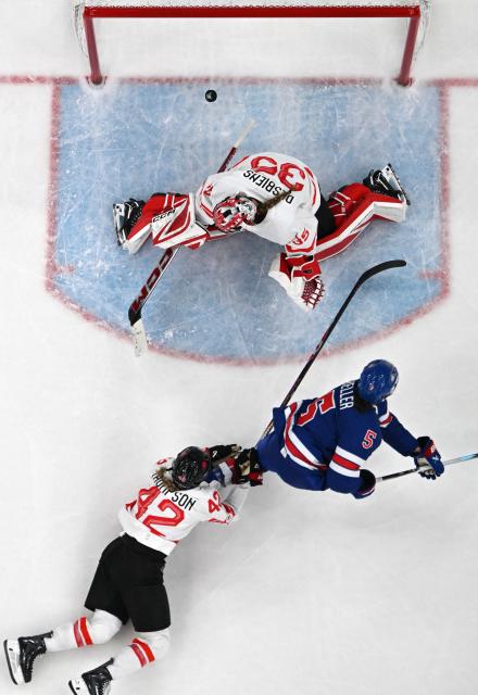USA's #05 Megan Keller (C) scores 2-1 against Canada's #35 Ann-Renee Desbiens in overtime during the women's gold medal ice hockey match between USA and Canada at the Milano Santagiulia Ice Hockey Arena during the Milano Cortina 2026 Winter Olympic Games in Milan, on February 19, 2026. (Photo by Alexander NEMENOV / AFP)