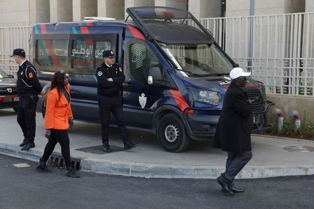 Members of the Senegalese Football Federation walk as police arrive with Senegalese football supporters at the Court of First Instance in Rabat on February 19, 2026. A Moroccan court on February 19 sentenced 18 Senegalese football fans to prison terms ranging from three to 12 months over hooliganism charges. The group had been in pre-trial detention since January 18, the day of the heated AFCON final in which Morocco lost to Senegal 1-0 on home turf, after some Senegalese supporters attempted a pitch invasion while others threw objects onto the field. (Photo by Abdel Majid BZIOUAT / AFP)