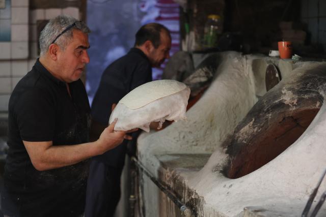 An Iraqi baker places the dough inside a stone oven to bake in his bakery during the Muslim holy fasting month of Ramadan in Baghdad on February 19, 2026. Muslims throughout the world are marking the month of Ramadan, the holiest month in the Islamic calendar, during which devotees fast from dawn until dusk. (Photo by AHMAD AL-RUBAYE / AFP)