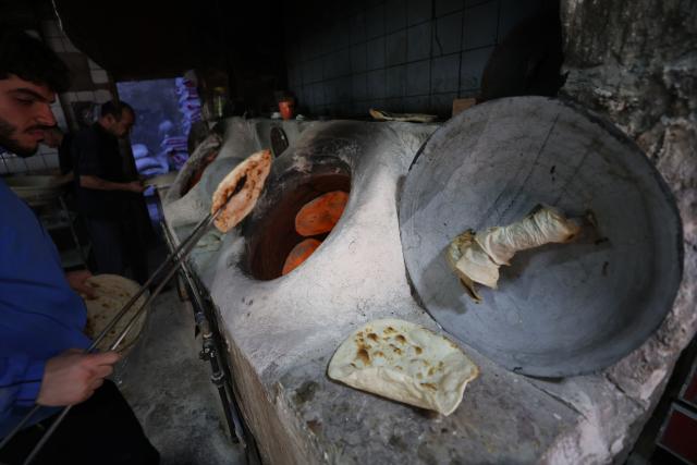 An Iraqi baker takes out the bread from a stone oven in his bakery during the Muslim holy fasting month of Ramadan in Baghdad on February 19, 2026. Muslims throughout the world are marking the month of Ramadan, the holiest month in the Islamic calendar, during which devotees fast from dawn until dusk. (Photo by AHMAD AL-RUBAYE / AFP)