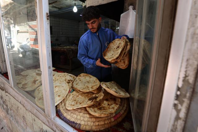 An Iraqi baker takes out the bread from a stone oven in his bakery during the Muslim holy fasting month of Ramadan in Baghdad on February 19, 2026. Muslims throughout the world are marking the month of Ramadan, the holiest month in the Islamic calendar, during which devotees fast from dawn until dusk. (Photo by AHMAD AL-RUBAYE / AFP)