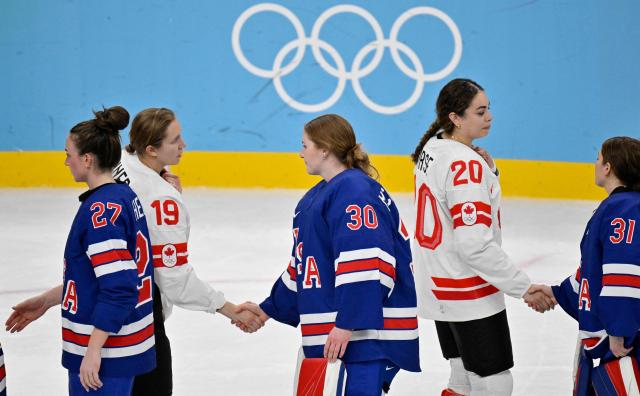 Players of Team USA and Team Canada shake hands prior to the medal ceremony for the women's ice hockey at the Milano Santagiulia Ice Hockey Arena during the Milano Cortina 2026 Winter Olympic Games in Milan, on February 19, 2026. (Photo by Alexander NEMENOV / AFP)