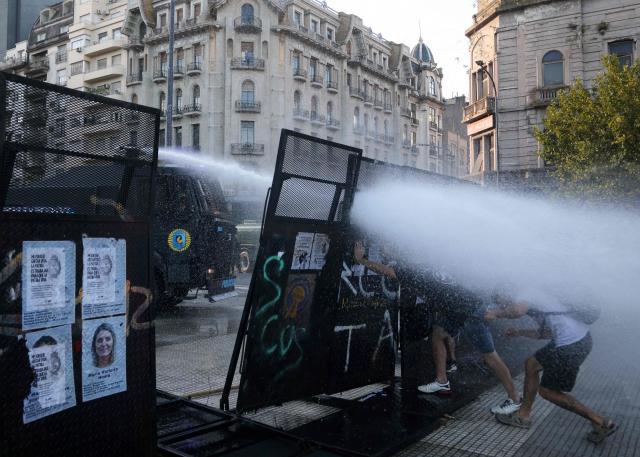 Demonstrators push a fence as a water canon attempts to disperse them during a protest outside the Congress building, where Argentina's President Javier Milei's labour reform is being treated, in Buenos Aires on February 19, 2026. The contested reforms pushed by Argentina's President Javier Milei would make it easier to hire and fire workers in a country where job security is already hard to come by. It would also reduce severance pay, limit the right to strike, increase work hours and restrict holiday provisions. (Photo by TOMAS CUESTA / AFP)