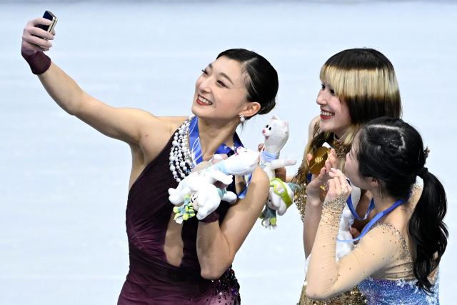 (From L) Silver medallist Japan's Kaori Sakamoto, gold medallist USA's Alysa Liu and bronze medallist Japan's Ami Nakai pose for a selfie on the podium of the figure skating women's single free skating final during the Milano Cortina 2026 Winter Olympic Games at Milano Ice Skating Arena in Milan on February 19, 2026. (Photo by WANG Zhao / AFP)