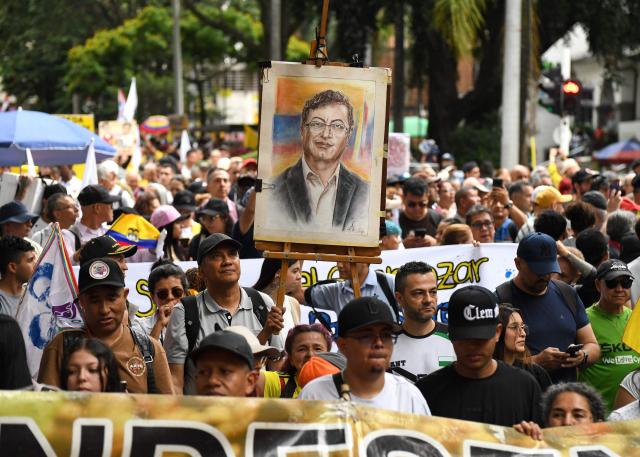 Supporters of Colombian President Gustavo Petro show a portrait of him during a demonstration in Medellin, Colombia on February 19, 2026, to back the vital minimum wage decree, which was provisionally suspended by the Council of State. (Photo by Jaime SALDARRIAGA / AFP)