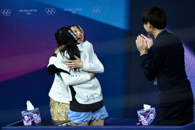Japan's Ami Nakai (C) reacts in the kiss and cry area next to USA's Alysa Liu (L) after competing in the figure skating women's single free skating final during the Milano Cortina 2026 Winter Olympic Games at Milano Ice Skating Arena in Milan on February 19, 2026. (Photo by WANG Zhao / AFP)