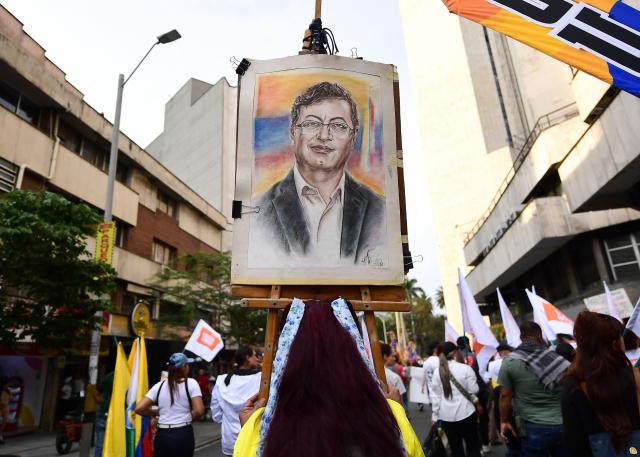 Supporters of Colombian President Gustavo Petro show a portrait of him during a demonstration in Medellin, Colombia on February 19, 2026, to back the vital minimum wage decree, which was provisionally suspended by the Council of State. (Photo by Jaime SALDARRIAGA / AFP)