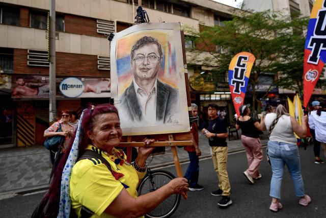 A woman shows a portrait of Colombian President Gustavo Petro during a demonstration in Medellin, Colombia on February 19, 2026, to back the vital minimum wage decree, which was provisionally suspended by the Council of State. (Photo by Jaime SALDARRIAGA / AFP)