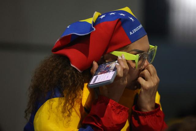 A relative watches on a cellphone the livestream of Venezuela’s National Assembly President Jorge Rodriguez speaking during a debate on an amnesty bill proposed by Venezuela’s interim president Delcy Rodriguez, outside the El Helicoide building, headquarters of the Bolivarian National Intelligence Service (SEBIN), in Caracas on February 19, 2026. Venezuela's Parliament resumed on February 19 the debate on an amnesty bill that could free hundreds of political prisoners. (Photo by Pedro MATTEY / AFP)