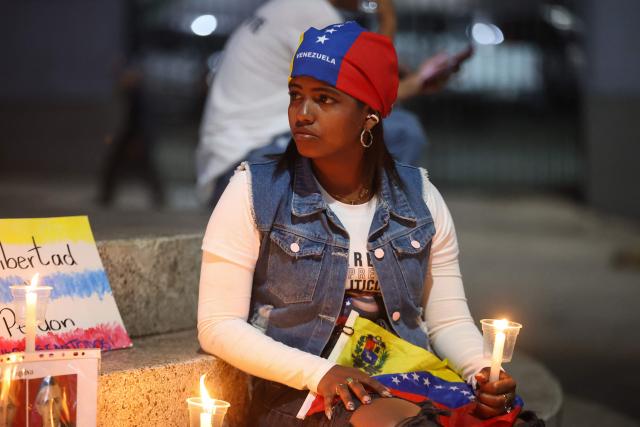 A relative of a political prisoner waits during the broadcast of the speech by Venezuela’s National Assembly President Jorge Rodriguez, who is speaking during a debate on an amnesty bill proposed by Venezuela’s interim president Delcy Rodriguez, outside the El Helicoide building, headquarters of the Bolivarian National Intelligence Service (SEBIN), in Caracas, on February 19, 2026. Venezuela's Parliament resumed on February 19 the debate on an amnesty bill that could free hundreds of political prisoners. (Photo by Pedro MATTEY / AFP)