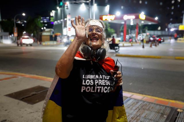 A woman shows a rosary outside the El Helicoide building, headquarters of the Bolivarian National Intelligence Service (SEBIN), in Caracas on February 19, 2026, as relatives of political prisoners follow the speech by Venezuela's National Assembly President Jorge Rodriguez, who is speaking during a debate on an amnesty bill proposed by interim president Delcy Rodriguez. Venezuela's Parliament unanimously approved on February 19 a historic amnesty law that is expected to lead to the release of hundreds of political prisoners after 27 years of Chavismo. (Photo by Pedro MATTEY / AFP)