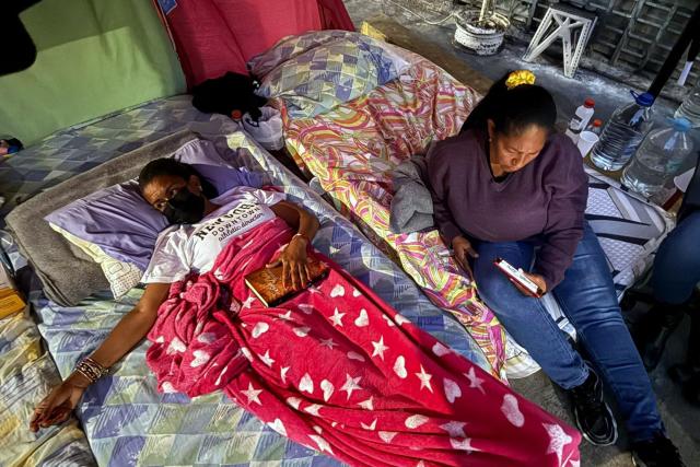 Relatives of political prisoners on hunger strike watch on a cellphone the livestream of Venezuela's National Assembly debate, as lawmakers discuss an amnesty bill proposed by interim president Delcy Rodriguez, outside the Bolivarian National Police (PNB) Zona 7 prison in Caracas on February 19, 2026. Venezuela's Parliament unanimously approved on February 19 a historic amnesty law that is expected to lead to the release of hundreds of political prisoners after 27 years of Chavismo. (Photo by Yorman MALDONADO / AFP)