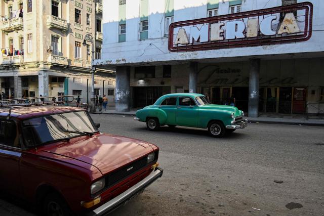 Cars drive past America Theater in Havana on February 19, 2026. (Photo by Yamil LAGE / AFP)