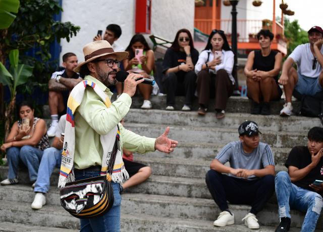 A tour guide speaks to a group of tourists in El Pueblito Paisa, known for being a scale replica of a traditional 20th-century Antioquian village, located atop Cerro Nutibara in Medellin, Colombia on February 18, 2026. (Photo by JAIME SALDARRIAGA / AFP)