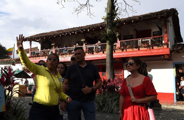 A tour guide speaks to a group of tourists in El Pueblito Paisa, known for being a scale replica of a traditional 20th-century Antioquian village, located atop Cerro Nutibara in Medellin, Colombia on February 18, 2026. (Photo by JAIME SALDARRIAGA / AFP)
