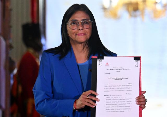 Venezuela's interim president Delcy Rodriguez holds the amnesty law approved by the National Assembly, at the Miraflores Palace in Caracas on February 19, 2026. Venezuela's Parliament unanimously approved on February 19 a historic amnesty law that is expected to lead to the release of hundreds of political prisoners after 27 years of Chavismo. (Photo by Juan BARRETO / AFP)