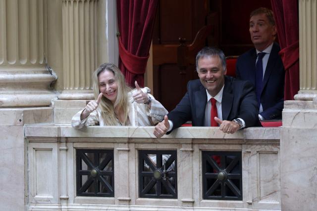 Argentina's Secretary General of the Presidency Karina Milei (L) and Chief of Cabinet and government spokesman Manuel Adorni (C) give thumbs up next to Interior Minister Diego Santilli (R) as they arrive at the chamber of deputies during a session to debate labor law reforms at the National Congress in Buenos Aires, early on February 20, 2026. The contested reforms pushed by Argentina's President Javier Milei would make it easier to hire and fire workers in a country where job security is already hard to come by. It would also reduce severance pay, limit the right to strike, increase work hours and restrict holiday provisions. (Photo by Tomas CUESTA / AFP)