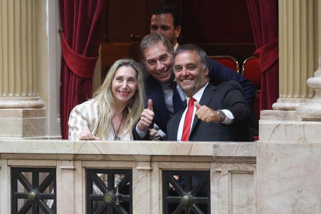 Argentina's Secretary General of the Presidency Karina Milei (L), Interior Minister Diego Santilli (C), and Chief of Cabinet and government spokesman Manuel Adorni (R) pose for a photo as they arrive at the chamber of deputies during a session to debate labor law reforms at the National Congress in Buenos Aires, early on February 20, 2026. The contested reforms pushed by Argentina's President Javier Milei would make it easier to hire and fire workers in a country where job security is already hard to come by. It would also reduce severance pay, limit the right to strike, increase work hours and restrict holiday provisions. (Photo by Tomas CUESTA / AFP)