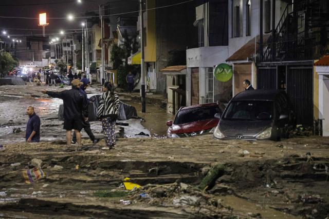 People look on next to cars and houses being affected by heavy rains in the Yanahuara district of Arequipa, southern Peru, on February 19, 2026 (Photo by Juan Santy / AFP)