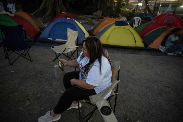 A relative of political prisoners watches on a cellphone the livestream of Venezuela’s National Assembly President Jorge Rodriguez speaking during a debate on an amnesty bill proposed by Venezuela’s interim president Delcy Rodriguez, outside El Rodeo I prison in Guatire, Miranda state, Venezuela, on February 20, 2026. Venezuela's Parliament unanimously approved on February 19 a historic amnesty law that is expected to lead to the release of hundreds of political prisoners after 27 years of Chavismo. (Photo by Pedro MATTEY / AFP)