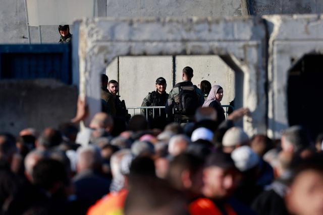 Israeli soliders keep watch as Palestinian Muslims gather at the Qalandia checkpoint in the occupied West Bank city of Ramallah on February 20, 2026, to enter Jerusalem on their way to Al-Aqsa Mosque for the first Friday noon prayers of the Islamic holy month of Ramadan. (Photo by Jaafar ASHTIYEH / AFP)
