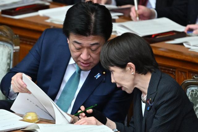 Japan's Prime Minister Sanae Takaichi (R) chats with Chief Cabinet Secretary Minoru Kihara during the House of Representatives plenary session in Tokyo on February 20, 2026. (Photo by Kazuhiro NOGI / AFP)
