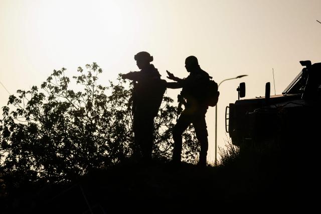 Israeli soldiers keep watch as Palestinian Muslims gather at the Qalandia checkpoint in the occupied West Bank city of Ramallah on February 20, 2026, to enter Jerusalem on their way to Al-Aqsa Mosque for the first Friday noon prayers of the Islamic holy month of Ramadan. (Photo by Jaafar ASHTIYEH / AFP)