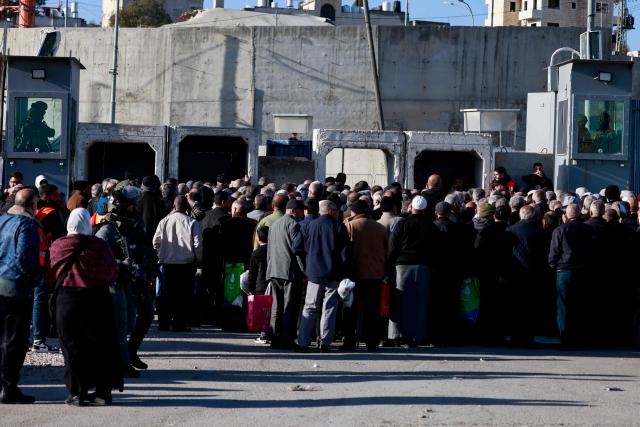 Israeli soldiers keep watch as Palestinian Muslims gather at the Qalandia checkpoint in the occupied West Bank city of Ramallah on February 20, 2026, to enter Jerusalem on their way to Al-Aqsa Mosque for the first Friday noon prayers of the Islamic holy month of Ramadan. (Photo by Jaafar ASHTIYEH / AFP)