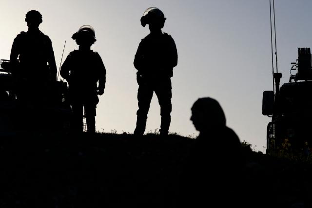 Israeli soldiers keep watch as Palestinian Muslims gather at the Qalandia checkpoint in the occupied West Bank city of Ramallah on February 20, 2026, to enter Jerusalem on their way to Al-Aqsa Mosque for the first Friday noon prayers of the Islamic holy month of Ramadan. (Photo by Jaafar ASHTIYEH / AFP)