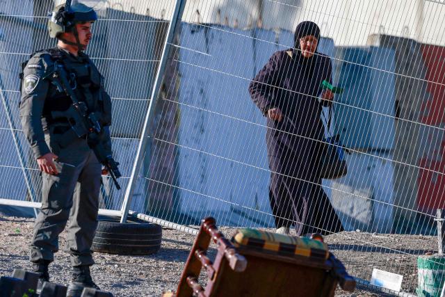 An Israeli soldier keeps watch as a Palestinian woman arrives at the Qalandia checkpoint in the occupied West Bank city of Ramallah on February 20, 2026, to enter Jerusalem on her way to Al-Aqsa Mosque for the first Friday noon prayers of the Islamic holy month of Ramadan. (Photo by Jaafar ASHTIYEH / AFP)
