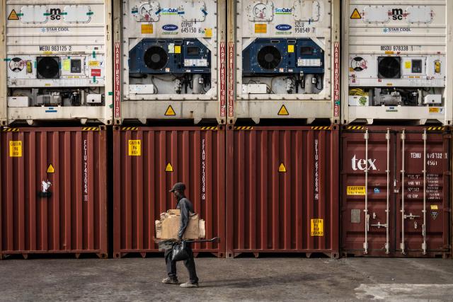 A worker walks next to containers stacked up at the Five Star Logistics terminal in Tin Can Island Port in Lagos, on February 19, 2026. (Photo by OLYMPIA DE MAISMONT / AFP)
