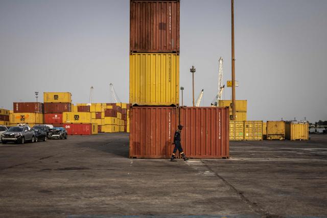 A security officer walks next to containers stacked up at the Five Star Logistics terminal in Tin Can Island Port in Lagos, on February 19, 2026. (Photo by OLYMPIA DE MAISMONT / AFP)