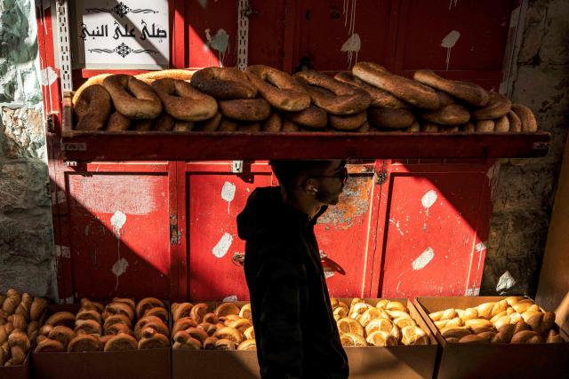 TOPSHOT - A man carries a tray of "kaak" bread through the old city of  Jerusalem on February 20, 2026. (Photo by JOHN WESSELS / AFP)