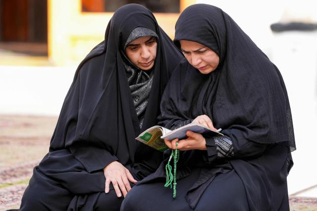 Muslim worshippers read from a booklet as they sit in Iraq's central holy city of Najaf on February 19, 2026 during the Muslim fasting month of Ramadan. (Photo by Qassem al-KAABI / AFP)