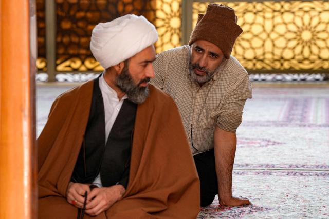 A man speaks with a Shiite Muslim cleric at a mosque in Iraq's central holy city of Najaf on February 19, 2026 during the Muslim fasting month of Ramadan. (Photo by Qassem al-KAABI / AFP)