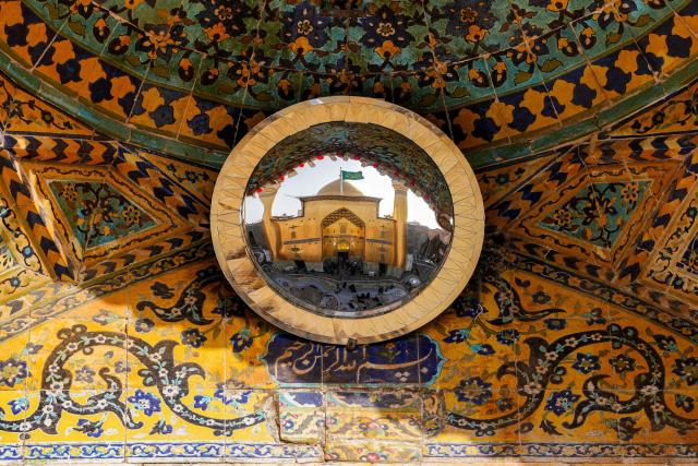 Pilgrims are pictured in a convex mirror visiting the Imam Ali Shrine in Iraq's central holy city of Najaf on February 19, 2026 during the Muslim fasting month of Ramadan. (Photo by Qassem al-KAABI / AFP)