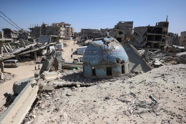 Dispalced Palestinians walk past the destroyed Al-Huda Mosque on the first Friday noon prayers of the holy month of Ramadan, in Khan Yunis in the southern Gaza Strip on February 20, 2026. Nearly all of Gaza's 2.2 million residents were displaced at least once during the more than two years of war between Israel and Hamas, sparked by the latter's unprecedented October 7 attack on Israel. (Photo by Bashar Taleb / AFP)