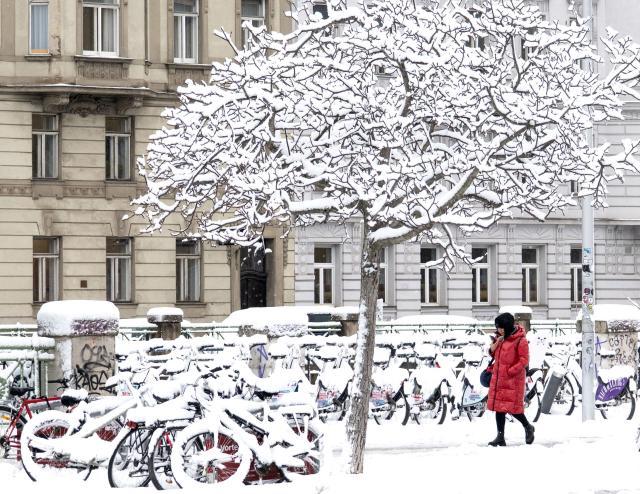 A woman walks through a snow covered street as winter strikes Vienna, Austria with snow and freezing temperatures on February 20, 2026. (Photo by Joe Klamar / AFP)