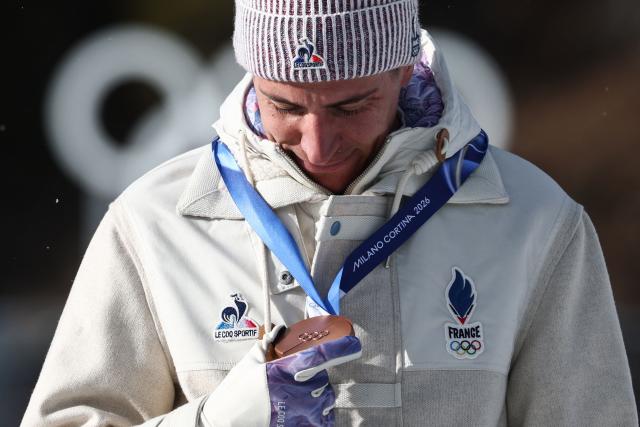Bronze medallist France's Quentin Fillon Maillet views his medal on the podium of the men's biathlon 15km mass start event during the Milano Cortina 2026 Winter Olympic Games at the Anterselva Biathlon Arena (Sudtirol Arena) in Anterselva (Val Pusteria) on February 20, 2026. (Photo by FRANCK FIFE / AFP)