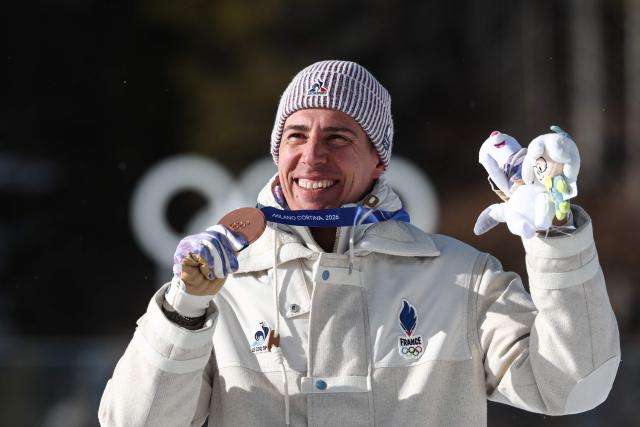 Bronze medallist France's Quentin Fillon Maillet celebrates with his medal on the podium of the men's biathlon 15km mass start event during the Milano Cortina 2026 Winter Olympic Games at the Anterselva Biathlon Arena (Sudtirol Arena) in Anterselva (Val Pusteria) on February 20, 2026. (Photo by FRANCK FIFE / AFP)