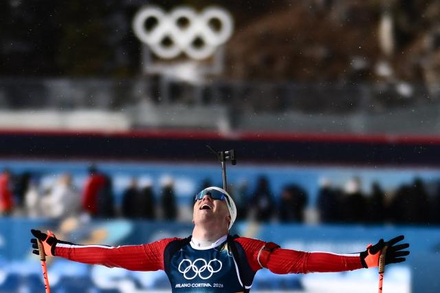Norway's Johannes Dale-Skjevdal celebrates as he crosses the finish line to win gold during the men's biathlon 15km mass start event during the Milano Cortina 2026 Winter Olympic Games at the Anterselva Biathlon Arena (Sudtirol Arena) in Anterselva (Val Pusteria) on February 20, 2026. (Photo by Marco BERTORELLO / AFP)