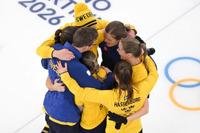 Sweden's Anna Hasselborg, Sweden's Sara McManus, Sweden's Agnes Knochenhauer and Sweden's Sofia Scharback celebrate with their teammates after winning the curling women's round robin semi-final between Canada and Sweden during the Milano Cortina 2026 Winter Olympic Games at the Cortina Curling Olympic Stadium in Cortina d’Ampezzo on February 20, 2026. (Photo by Antonin THUILLIER / AFP)