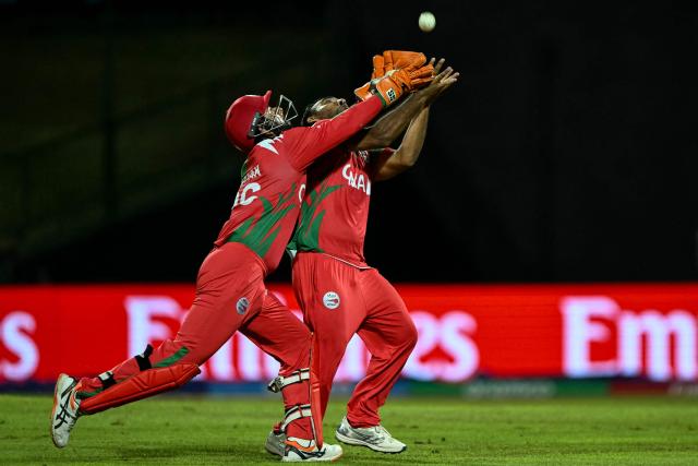 Oman's Shakeel Ahmed (R) and wicketkeeper Vinayak Shukla attempt to take a catch of Australia's Travis Head during the 2026 ICC Men's T20 Cricket World Cup group stage match between Oman and Australia at Pallekele International Cricket Stadium in Kandy on February 20, 2026. (Photo by Ishara S. KODIKARA / AFP)