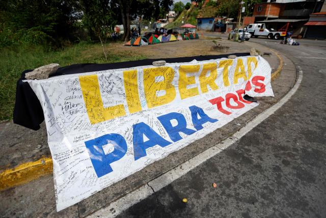 A banner reading "Freedom for all" is displayed in front of El Rodeo I prison in Guatire, Miranda state, Venezuela, on February 20, 2026. Venezuela's National Assembly on February 19 unanimously approved a long-awaited amnesty law that could free hundreds of political prisoners jailed for being government detractors. (Photo by Pedro MATTEY / AFP)