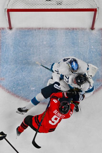 Canada's #09 Sam Bennett (bottom) collides with Finland's #77 Niko Mikkola (C) and Finland's #74 Juuse Saros during the men's play-off semi-final ice hockey match between Canada and Finland at the Milano Santagiulia Ice Hockey Arena during the Milano Cortina 2026 Winter Olympic Games in Milan, on February 20, 2026. (Photo by JULIEN DE ROSA / AFP)